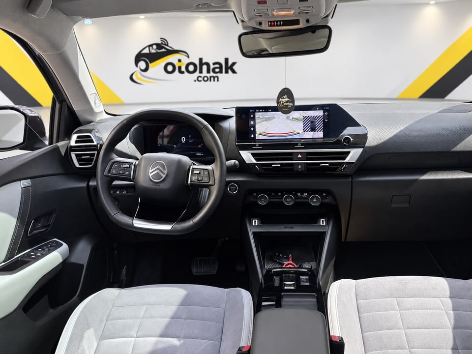 Gri Citroen e-C4 X'in ön konsolu ve direksiyonu