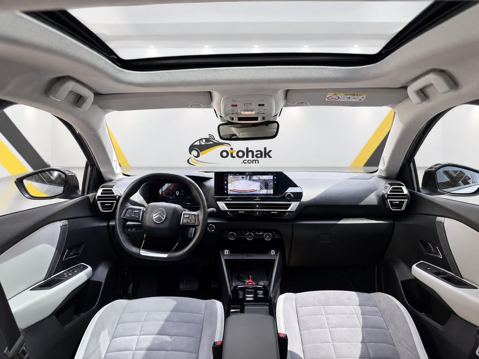 Gri Citroen e-C4 X'in panoramik cam tavanı ve ön kabini